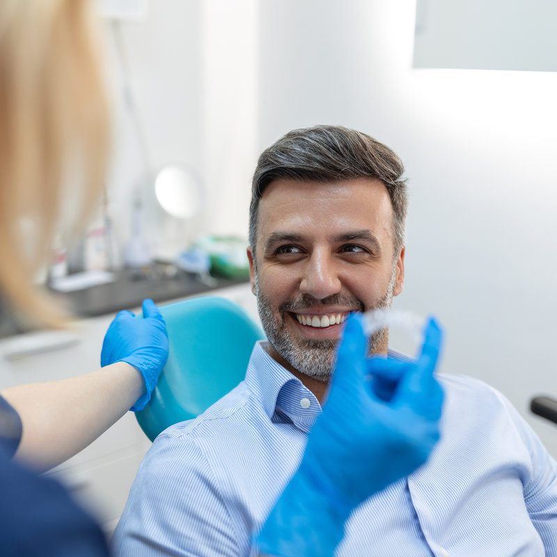 A young female dentist showing invisalign to patient in dental clinic, teeth check up and healthy teeth concept