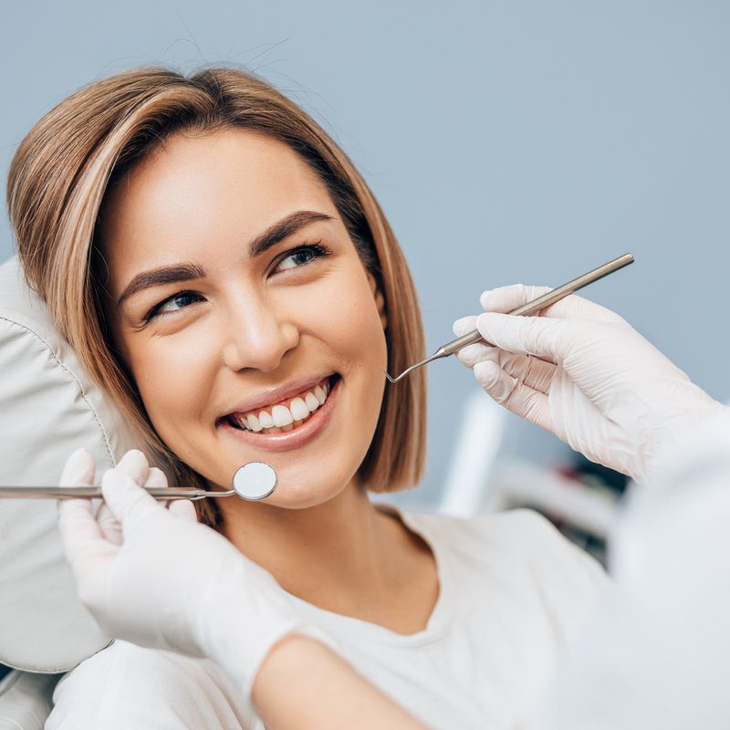 Portrait of young blond good-looking woman on dental examination, treating teeth in professional orthodontic clinic, look at doctor and smile