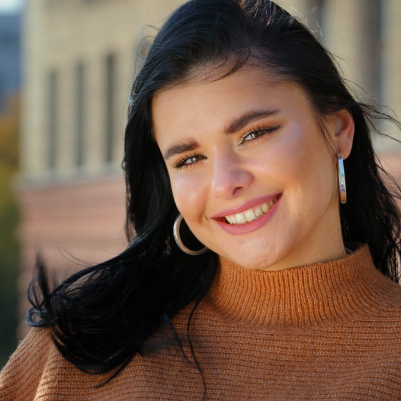 Young attractive hispanic girl student model looking at camera posing standing alone outdoors for close-up portrait professional beautiful smiling with white teeth dental smile happy carefree woman