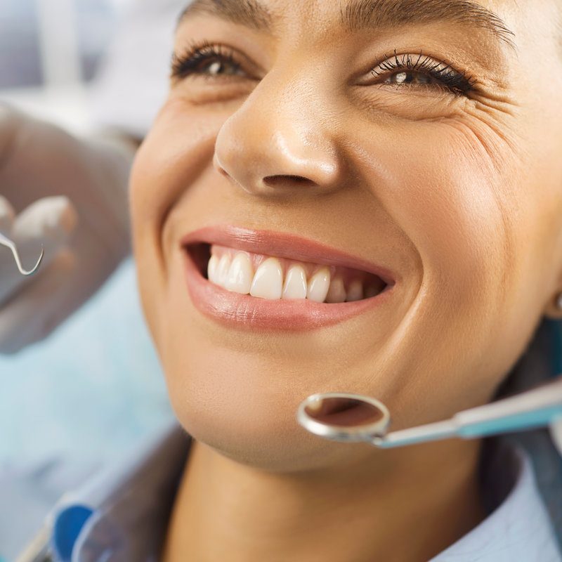 Close up shot of cheerful young woman being on dentist visit, undergoing dental treatment in medical clinic, demonstrating white perfect teeth. Dental care, hygiene and oral cavity concept