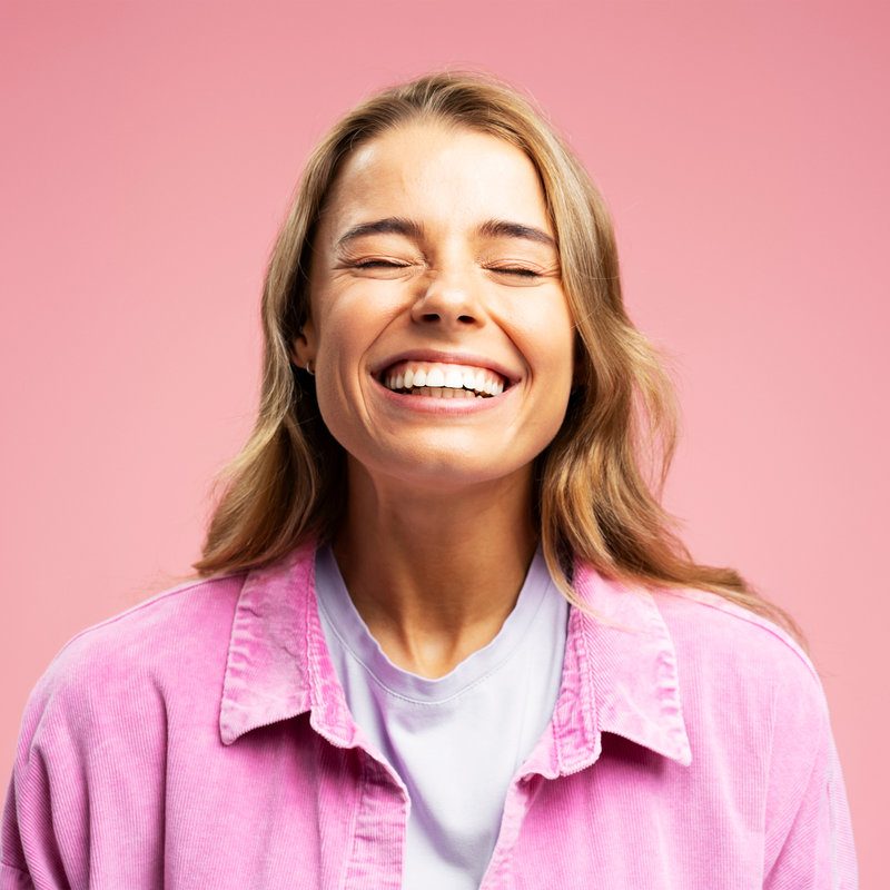 Closeup portrait of beautiful young woman with happy face, with white teeth isolated on pink background. Dental, teeth whitening concept