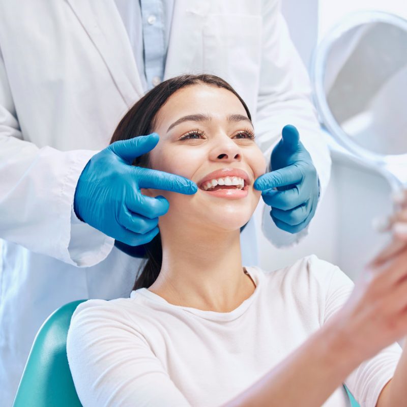 Dental consultation, mirror and woman with smile after teeth whitening, service or mouth care. Healthcare, dentistry and happy female patient with orthodontist for oral hygiene, wellness and cleaning