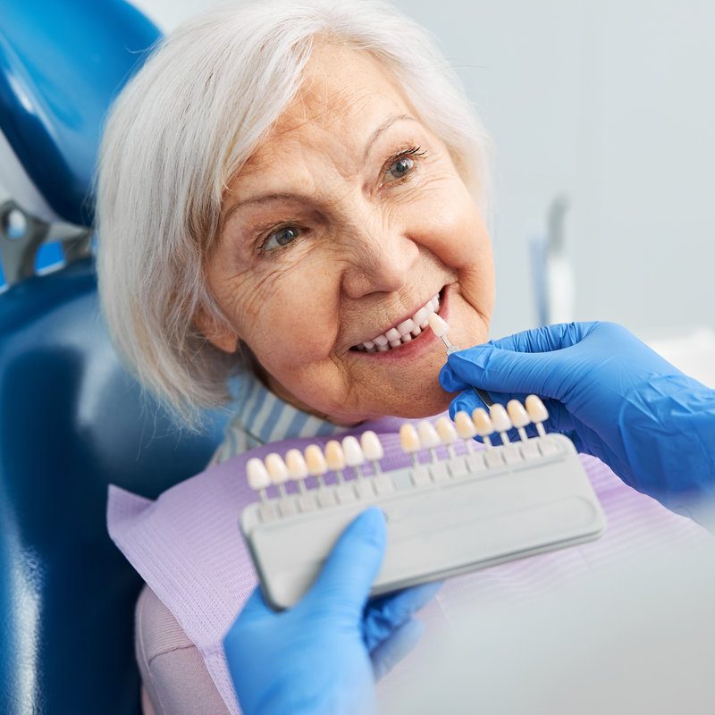 Dental professional matching tooth shade with pensioner teeth