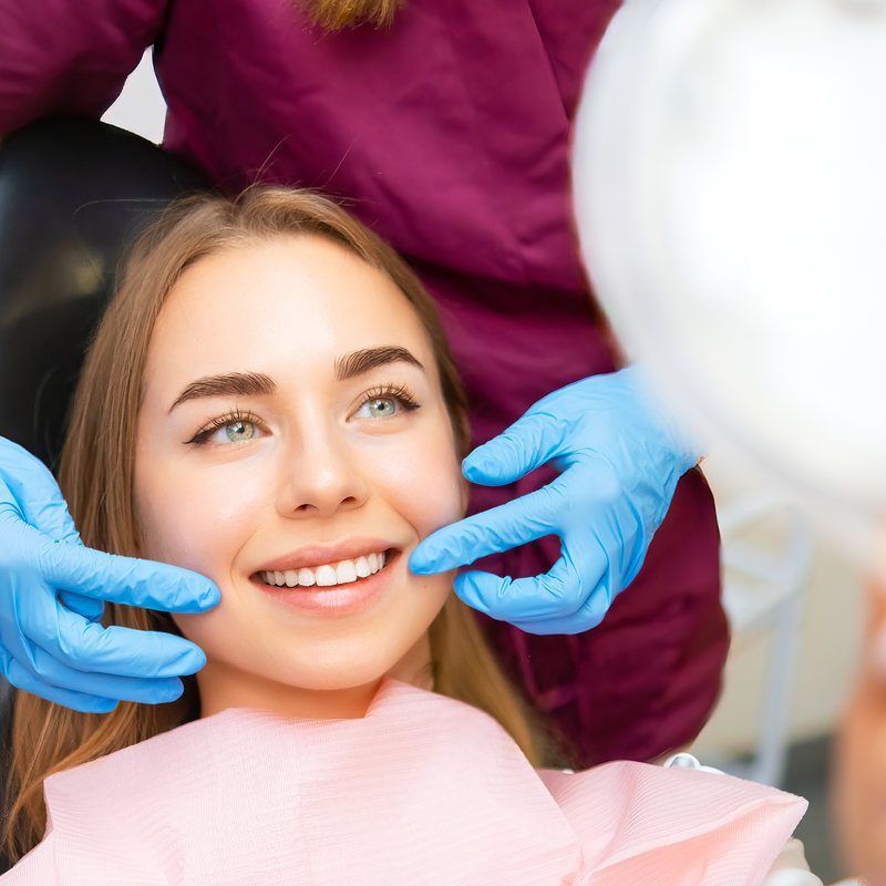 Dentist demonstrates the perfect smile of the patient after implatation of dental veneers or teeth whitening.