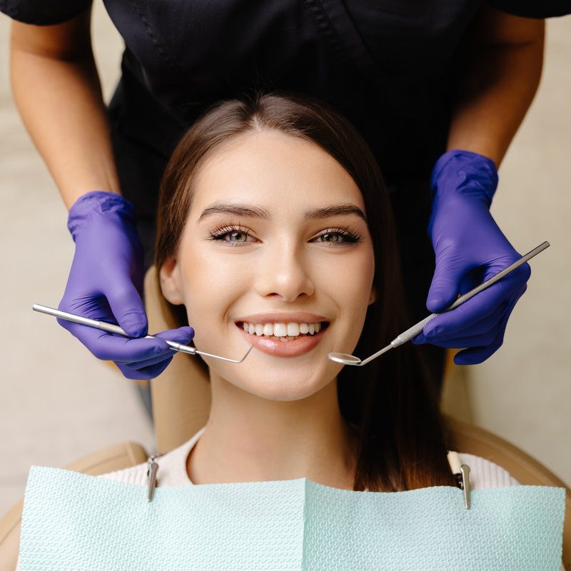 Happy patient during a visit to the dentist. The doctor is checking teeth using a dental instrument, ensuring proper oral care in the dentistry clinic