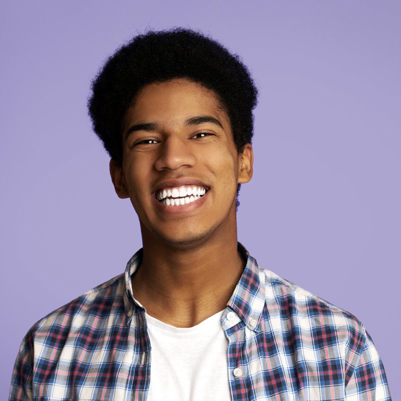 Perfect teeth. African american guy widely smiling over pink studio background