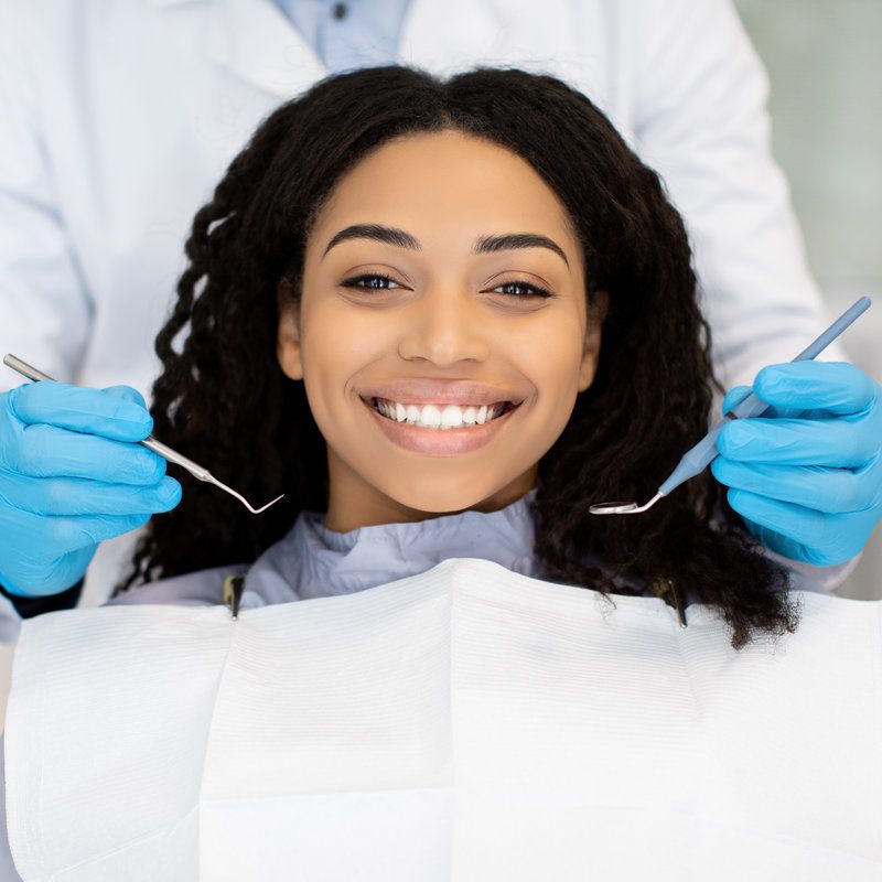 Portrait of happy young black woman having check up at dental clinic