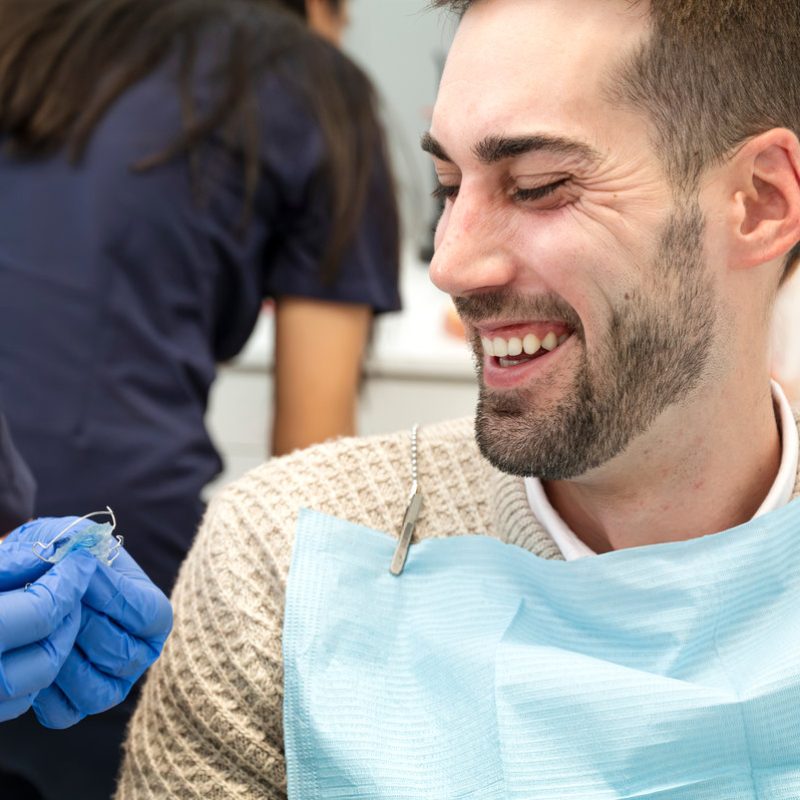 Smiling man in his 30s at a dental checkup with orthodontic retainer in clinic