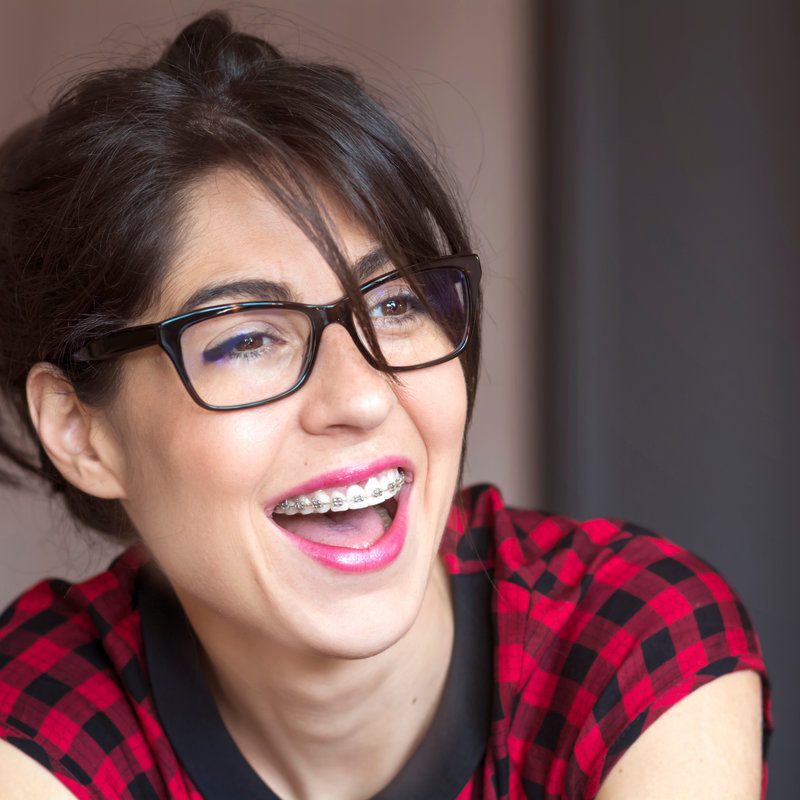 Beautiful smiling woman with braces on teeth. Orthodontic treatment. Dental care concept