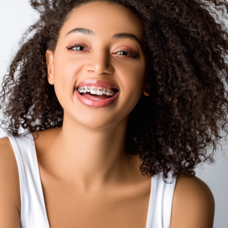 Laughing african american girl with dental braces, isolated on grey
